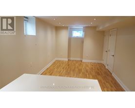 A room with wooden flooring and white walls, with a window and a door visible.