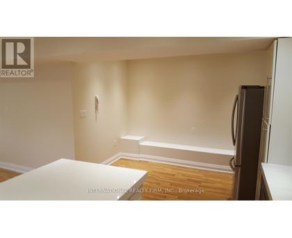 A white table is in the middle of a room with a refrigerator on the right.