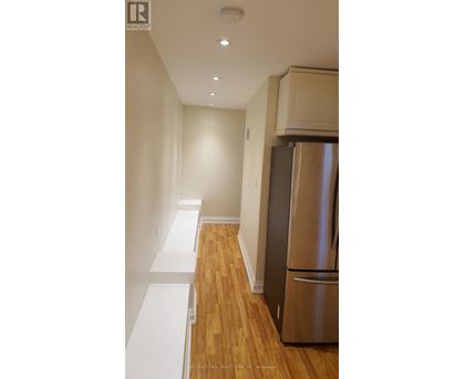 A stainless steel refrigerator in a kitchen with wooden floors and white walls.