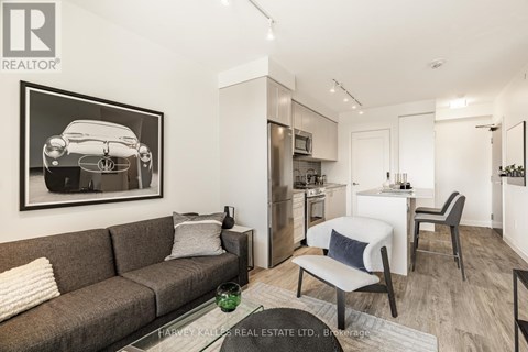 A living room with a grey couch and a framed picture of a car on the wall.