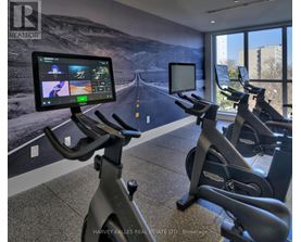A gym with exercise bikes and a screen showing a treadmill workout.