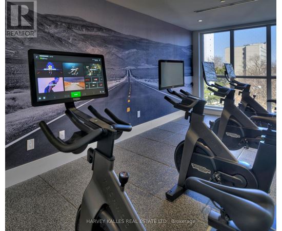 A gym with exercise bikes and a screen showing a treadmill workout.