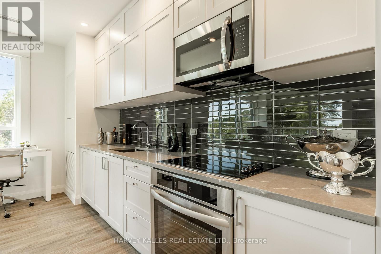 A modern kitchen with white cabinets and a glass backsplash.