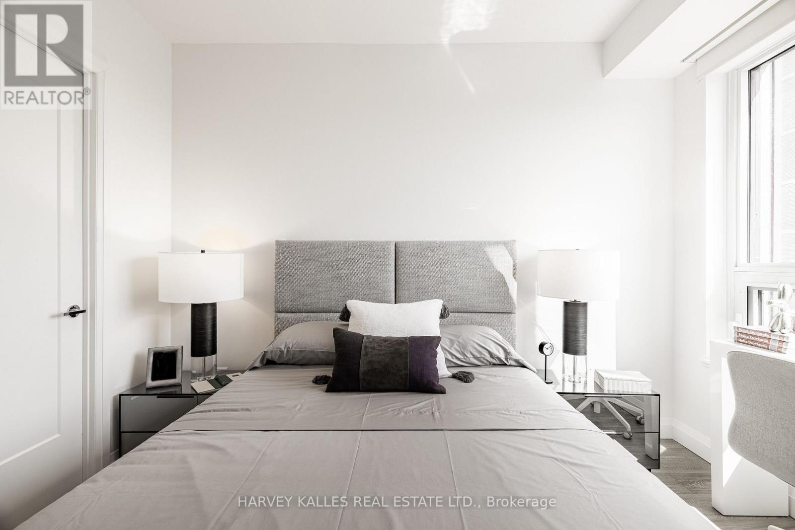 A bedroom with a large bed and two lamps.