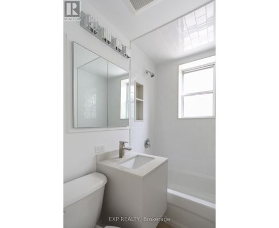 A white bathroom with a tub, sink, and mirror.