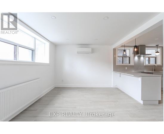 A spacious room with a window, a radiator, and a kitchenette.