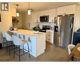 A kitchen with white cabinets and a stainless steel refrigerator.
