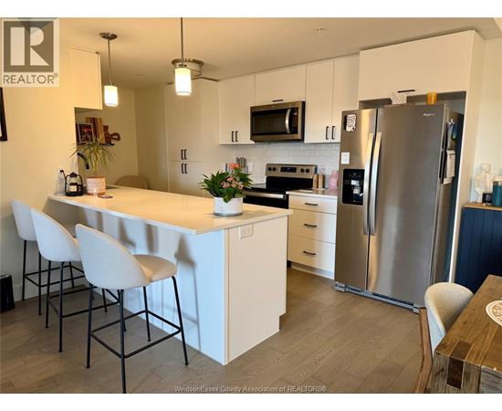 A kitchen with white cabinets and a stainless steel refrigerator.