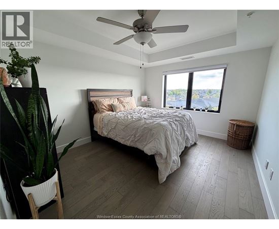 A bedroom with a bed, a plant, and a window.