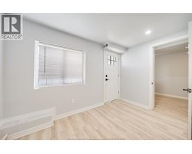 A room with a window, a door, and a wooden floor.