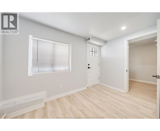 A room with a window, a door, and a wooden floor.