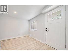 A white door is on the right side of a room with a window and a light on the wall.
