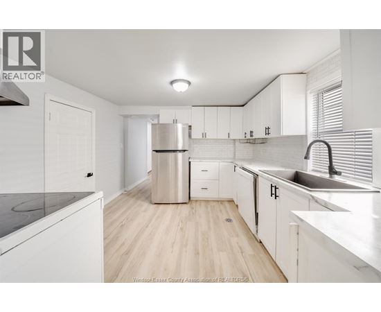 A kitchen with white cabinets and a wooden floor.