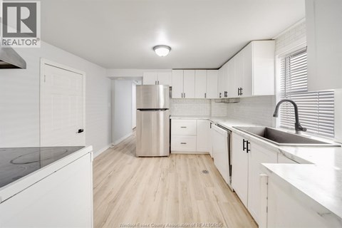 A kitchen with white cabinets and a wooden floor.