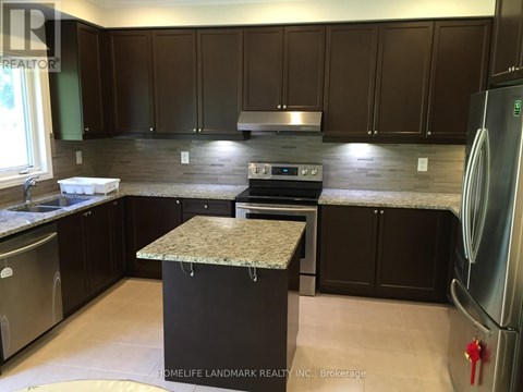 A kitchen with dark brown cabinets and a granite island.