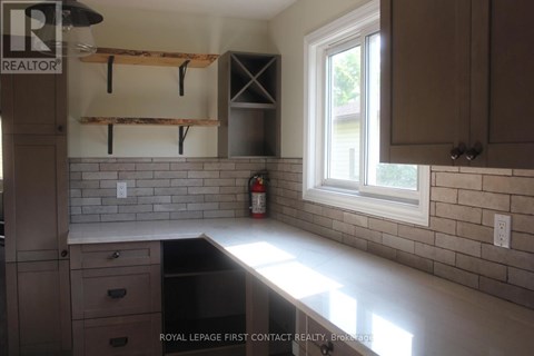 A kitchen with a black dishwasher and white countertops.