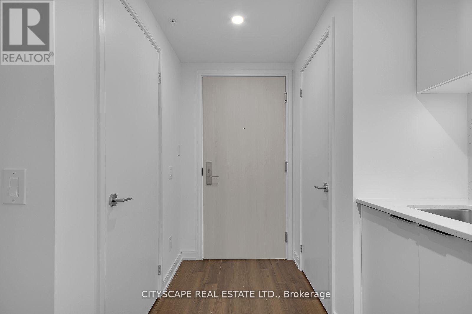 A white hallway with a door and a light on the ceiling.