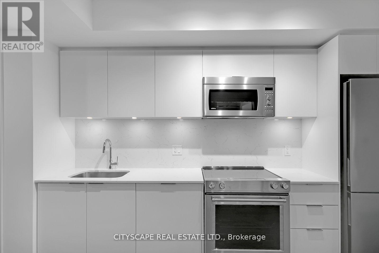 A modern kitchen with white cabinets and stainless steel appliances.