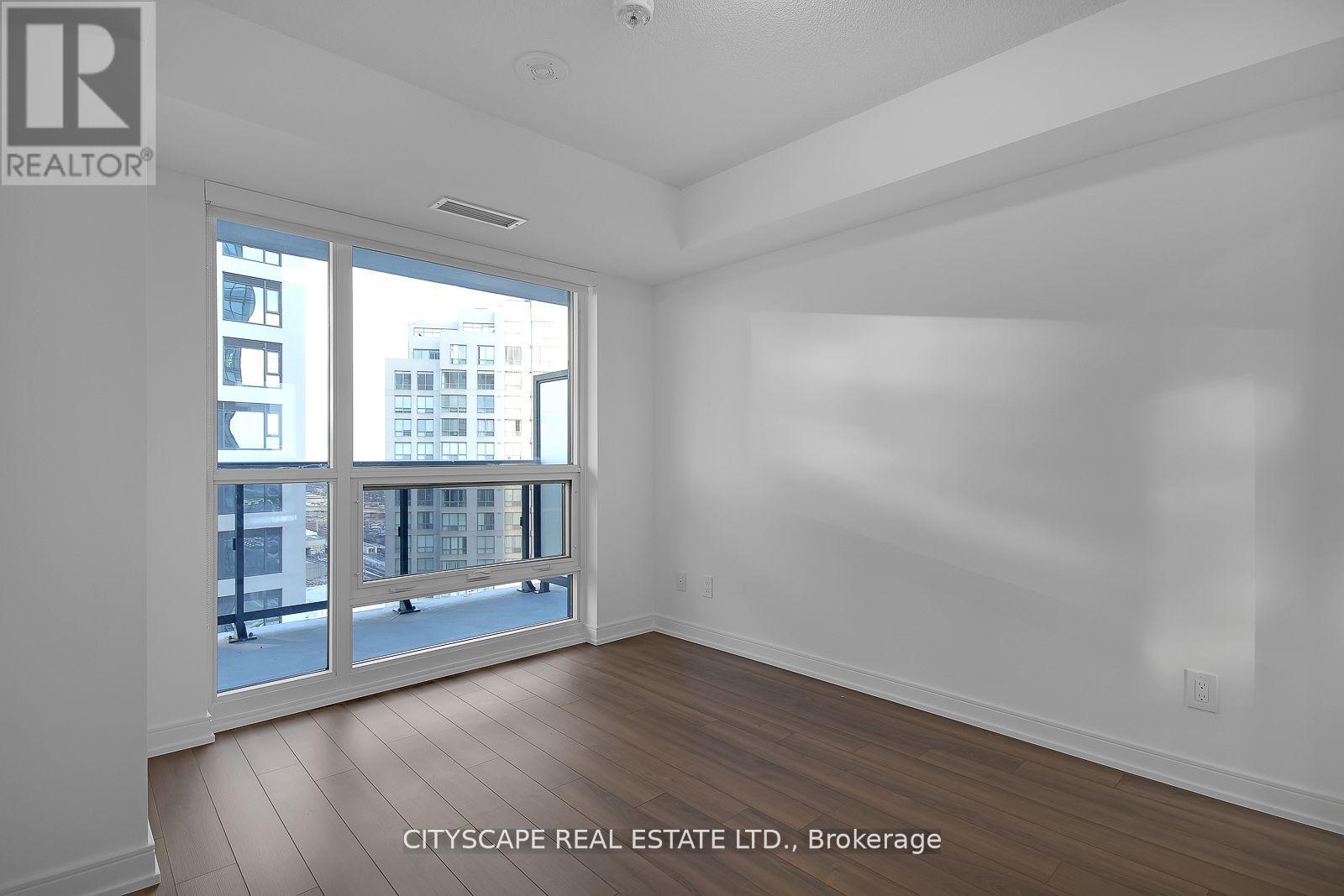 A spacious, empty room with a view of the cityscape outside.