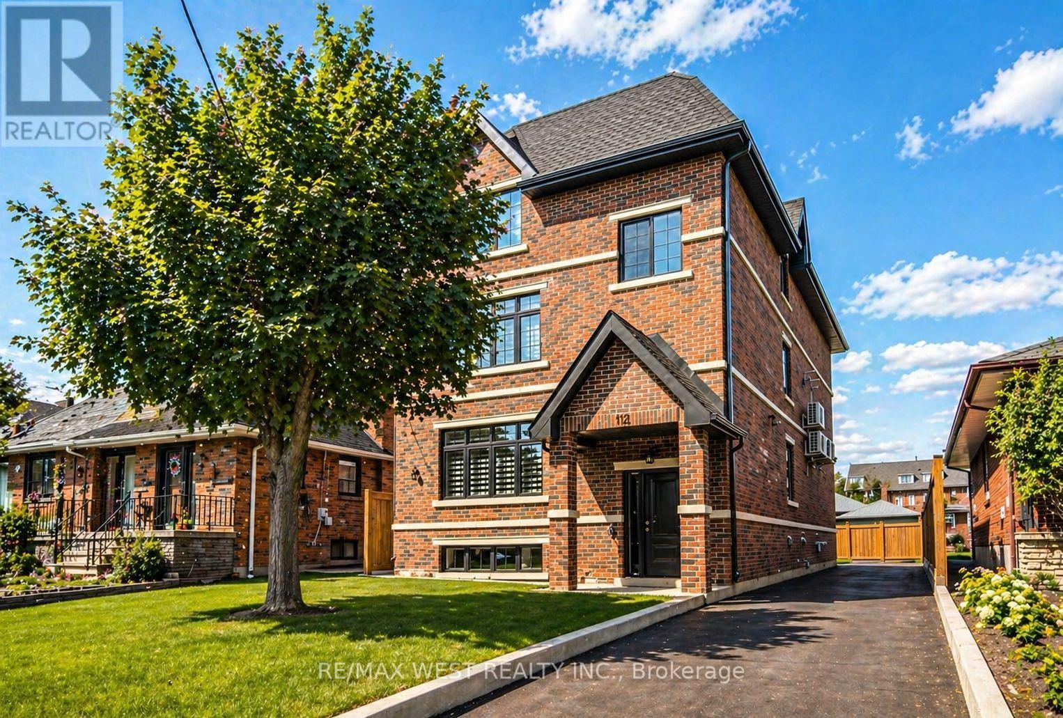 A large brick house with a tree in front.