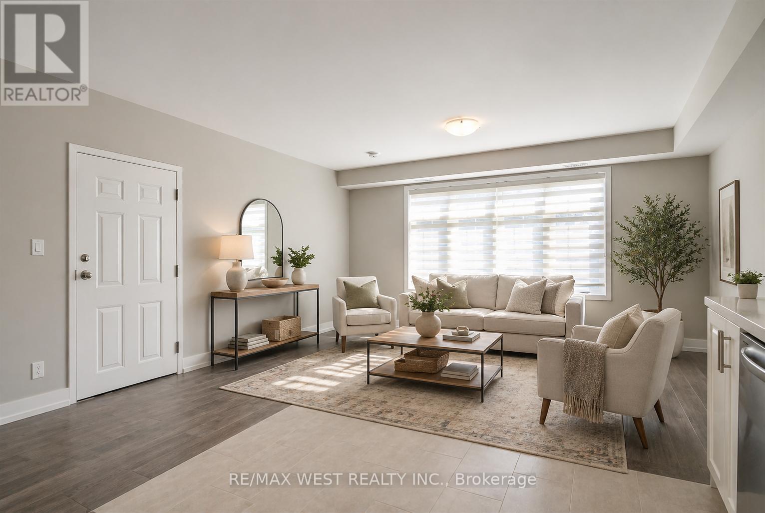 A well-lit living room with a white door, a table with a vase and a plant, and a couch with a throw pillow.