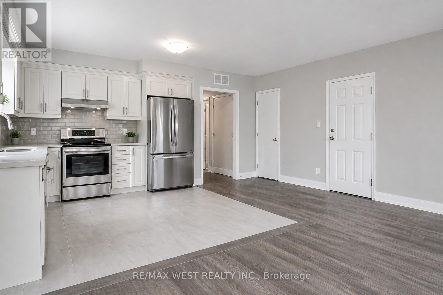 A kitchen with white cabinets and a stainless steel refrigerator.