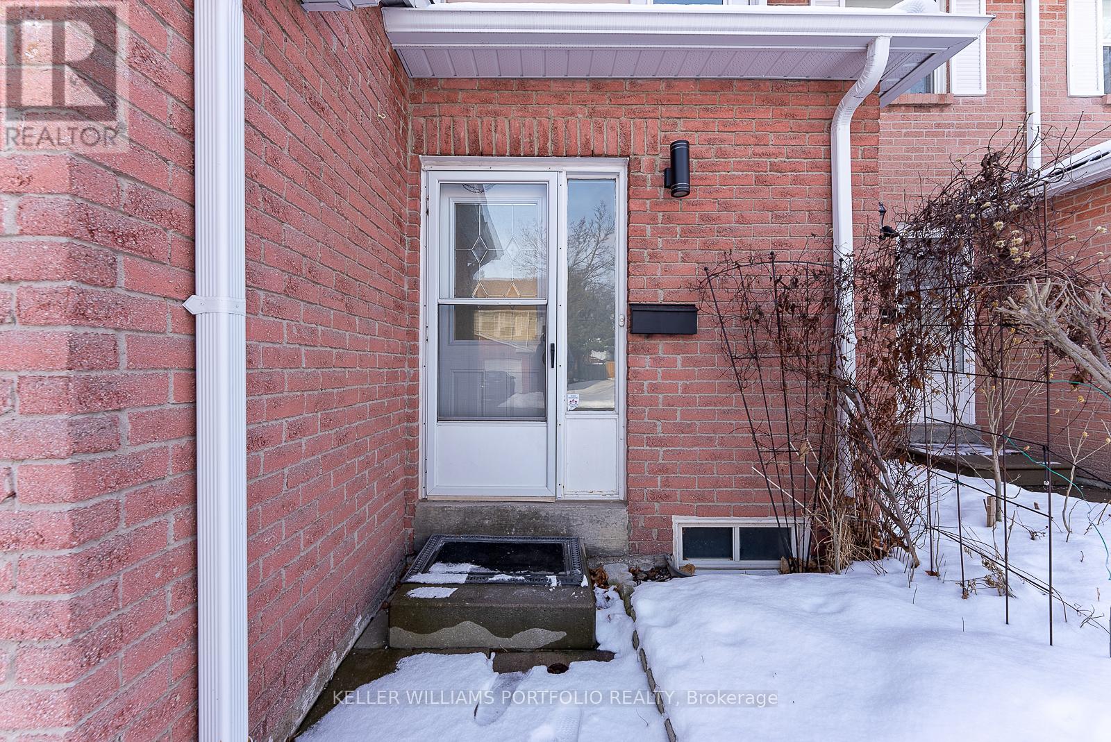 A red brick house with a white door and a window.