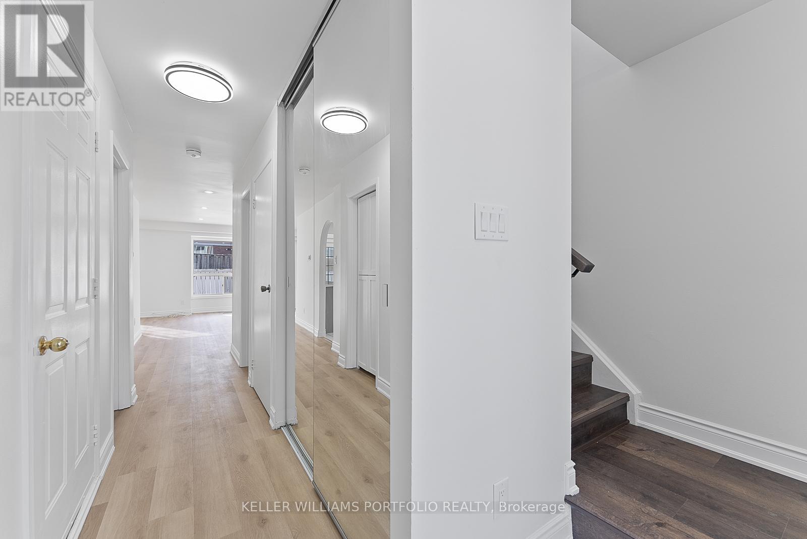 A hallway with white walls and wood floors.