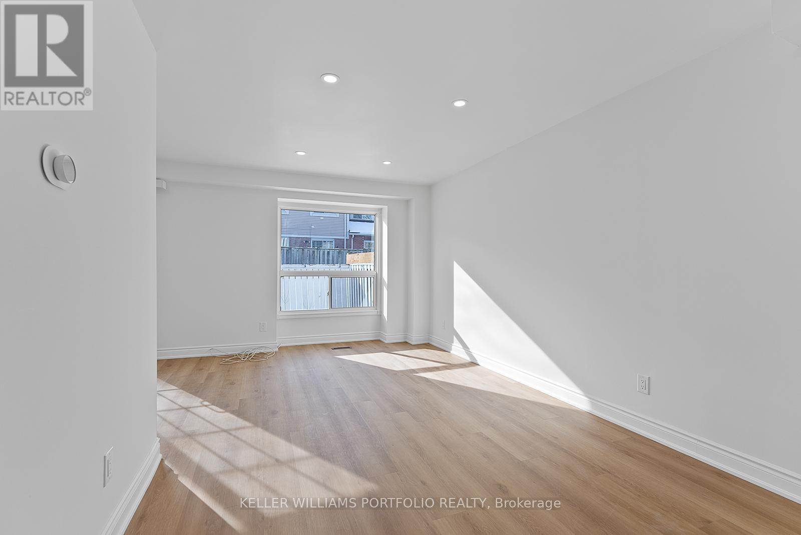 A spacious room with wooden floors and white walls.