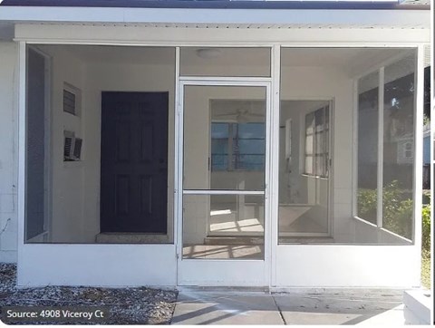 A white house with a black door and glass windows.