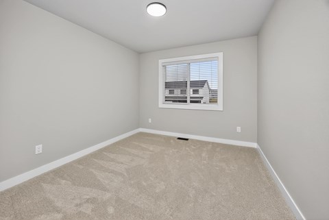 A room with a carpeted floor and a picture of a house on the wall.