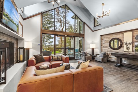 A living room with a brown leather couch and a large window.