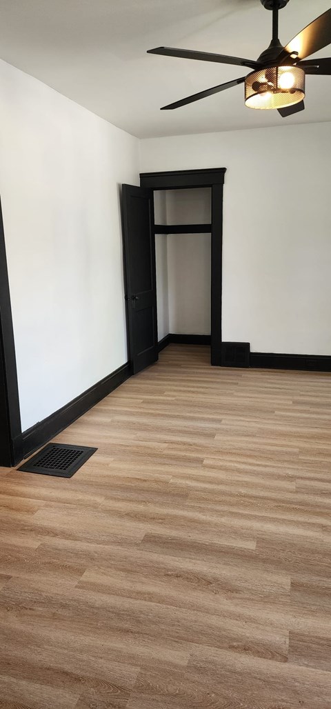 A room with a ceiling fan and a wooden floor.