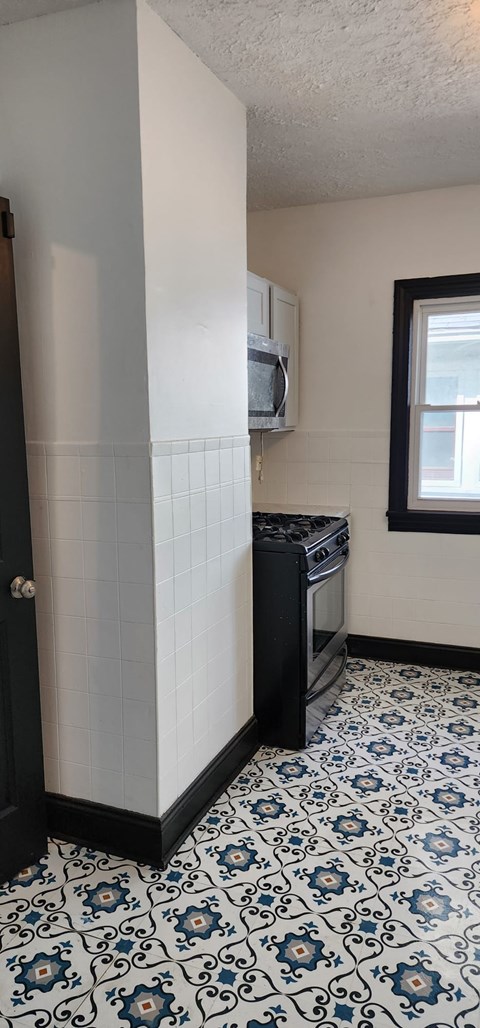 A kitchen with a black oven and a tiled floor.