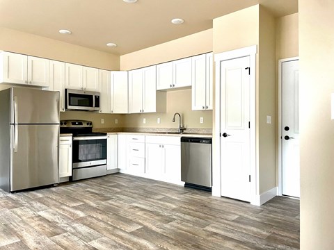 A kitchen with white cabinets and a wooden floor.
