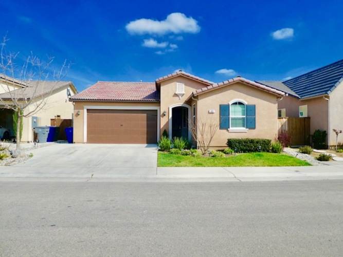 A house with a brown garage door and a red tile roof.