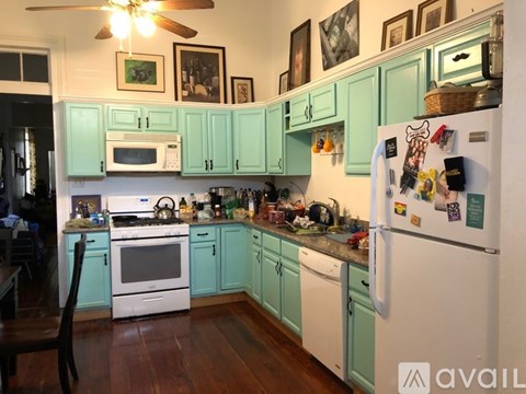 A kitchen with a white refrigerator and green cabinets.