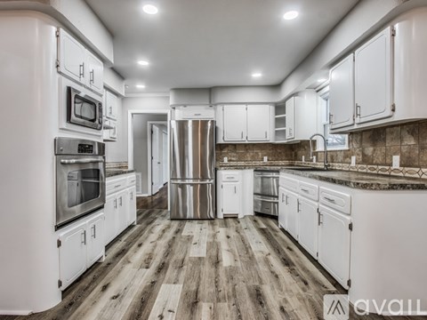 A kitchen with white cabinets and a wooden floor.