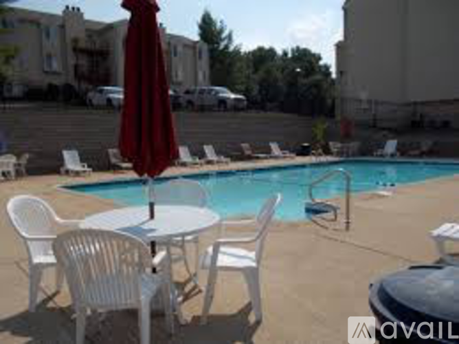 A pool with chairs and an umbrella is surrounded by buildings.