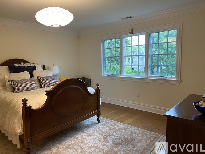 A bedroom with a large bed and a window overlooking a green area.