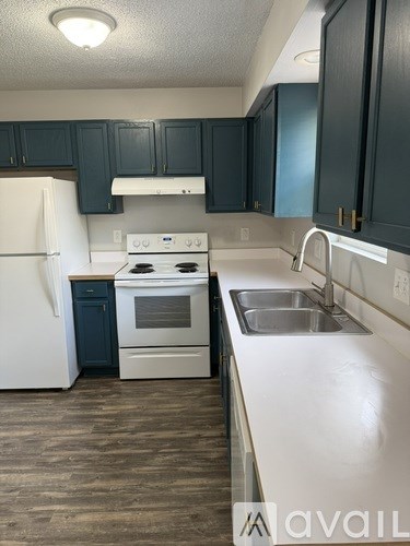 A kitchen with a white refrigerator, black cabinets, and a white stove top oven.