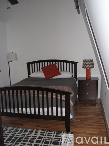 A bedroom with a bed, nightstand and lamp.