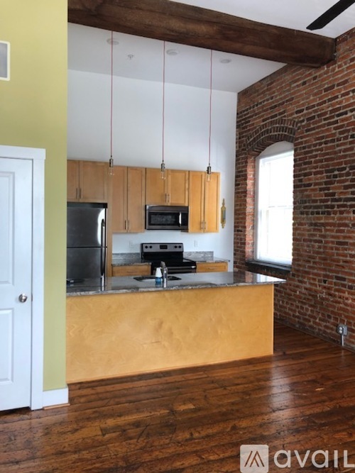 A kitchen with wooden cabinets and a brick wall.