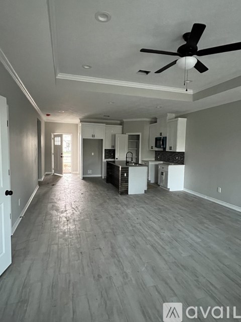 A spacious living room with a ceiling fan and lighting fixtures.