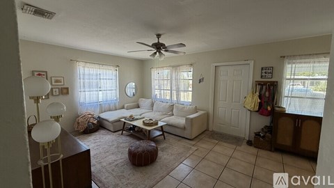 A living room with a white couch and a brown ottoman.