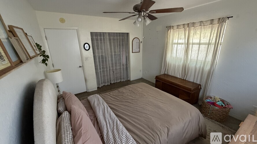 A bedroom with a bed, a ceiling fan, and a window with curtains.