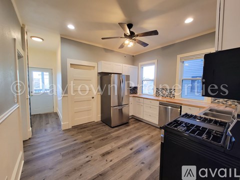 A kitchen with a black stove top oven and wooden flooring.