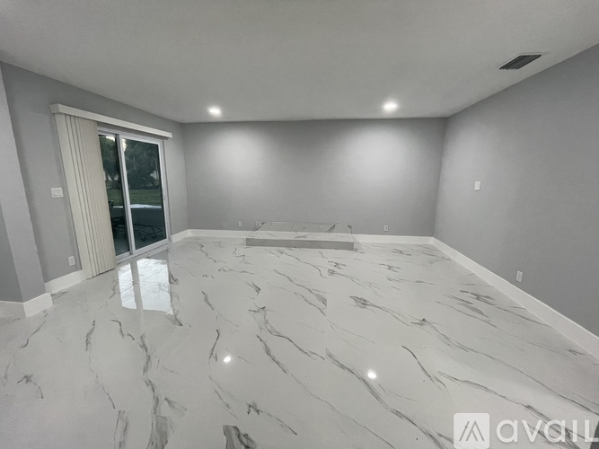 A spacious room with marble flooring and a sliding glass door.