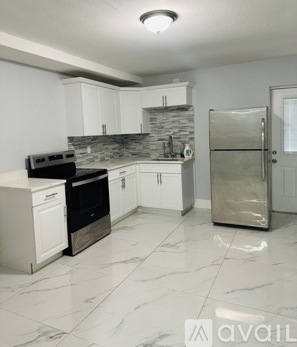 A kitchen with white cabinets and a marble floor.