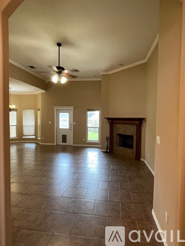 A spacious room with a fireplace and a ceiling fan.